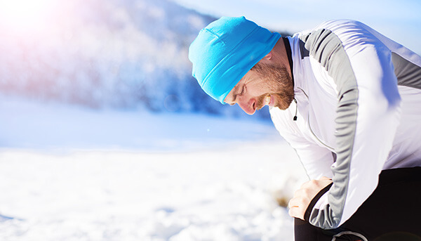 Man with knee pain while jogging in the snow