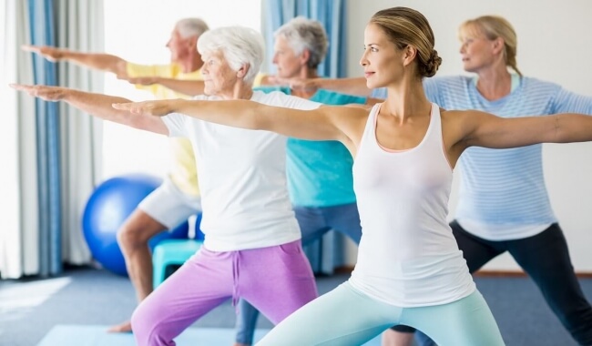 Group of elderly and young men and women doing yoga