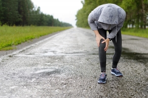 Jogger holding her knee on rainy day