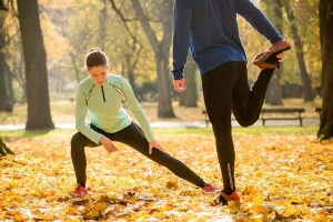Couple stretching before run in park in the fall